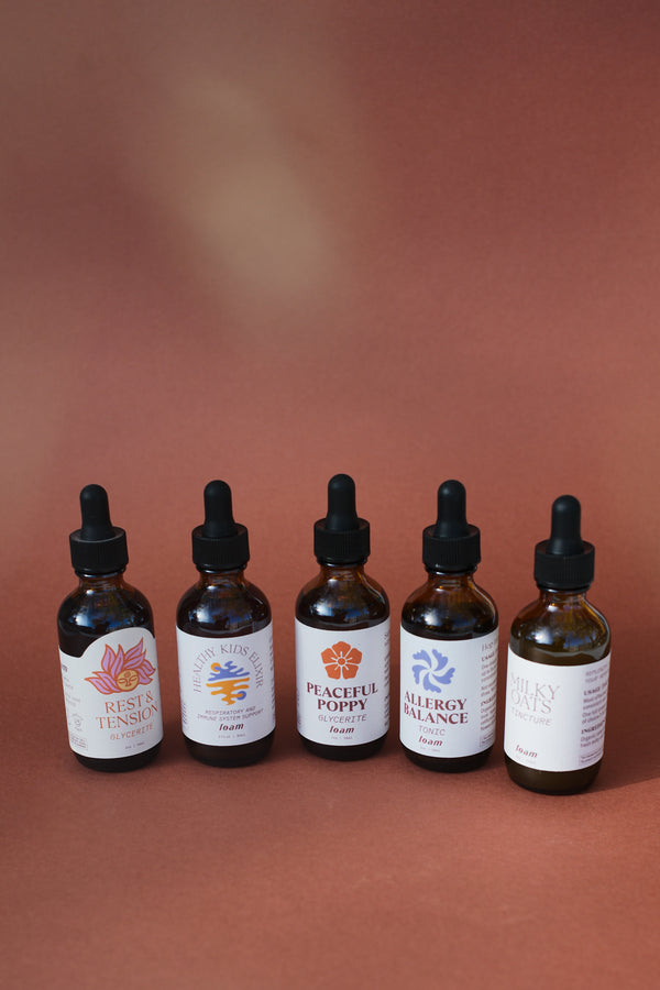 Apothecary bundle. Five amber glass bottles with black dropper lids on a brown background